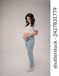 Small photo of Female waiting for newborn baby on white background. Pregnancy motherhood procreation concept. Belly of a pregnant woman. Young pregnant girl touching and holding belly and caring about health indoors