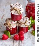 Small photo of Raspberry marmalade in small glasses is placed on wooden desk. Homemade jam from fresh raspberries. Fresh and healthy cooking.