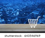 Shopping cart icon on wooden table over aerial of modern city tower, street and expressway, Shop online concept