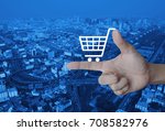 Shopping cart icon on finger over modern city tower, street and expressway, Shop online concept