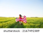 US Independence Day or Memorial Day. patriotic background with copy space. child girl with American flag runs across field in nature