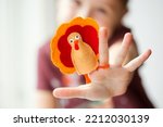 Small photo of craft for kids. DIY felt Turkey for thanksgiving day. create art for children. girl playing with finger toy.