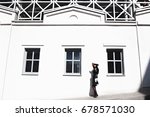 Elegant woman in the style of coco chanel near a white building with windows