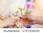 Close-up detail of men and woman hands clinking glasses of white champagne or prosecco at party or celebration event outdoors. People having fun enjoy drink alcohol toasting cheers at cafe restaurant