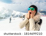 Portrait of beautiful young adult caucasian woman in sport suit, hat, sunglasses smiling looking aside and making excited amazed face expression on mountain peak sunny winter day alpine ski resort