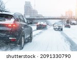 Scenic view snow covered city highway slippery road drive cars moving fast speed motion. Snowfall danger blizzard bad winter weather conditions. Urban cold snowy day snowstrom town background