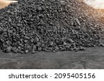 Big heap of dark black lump coal on floor bulk. Charcoal sorage at warehouse stock reserve. activated anthracite pile. Power and heat generation. Industrial and mining industry background