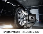 CLose-up car wheel indoors service maintenance repair center against laser sensor equipment diagnostics and 3d wheel alignment. Vehicle inside garage workshop for auto camber toe check fixing work