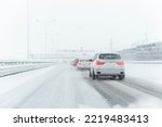 Scenic view snow covered intercity highway slippery snow covered road drive cars moving slowly. Snowfall danger blizzard bad winter weather conditions. Urban cold snowy day snowstrom town background