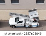 Small photo of Mover service lifting ladder cargo crane platform vehicle van parked at city street. Retractable furniture elevator machine car pickup truck rental company for relocation and house moving delivery