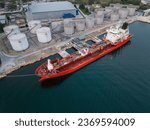 Small photo of Tanker ship refueling at an oil terminal with storage silo's in the port, aerial view
