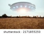 Small photo of UFO, an alien saucer hovering above the field in the clouds, hovering motionless in the sky. Unidentified flying object, alien invasion, extraterrestrial life, space travel, spaceship. mixed media
