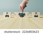 Small photo of The hand holds wooden wooden blocks with icons of a woman and a man and shaking hands in the act of consent. The concept of divorce, agreement, mediation, the role of the mediator.