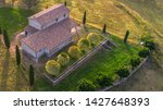 Aerial view of a villa at sunset. The country house has a large garden with trees and plants and is surrounded by nature in the hills of Tuscany, Italy. 