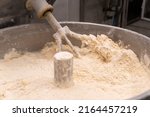 Small photo of Close-up of the process of kneading mixing bread dough in a kneading machine in a bakery. Industrial mixer for kneading dough. One of the stages of making bread dough