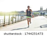 Small photo of Athlectic woman during her running cession along the river in the city