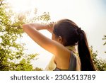 Small photo of Back view Asian woman doing sport jogging feeling sun and heat too hot during jogging in park sweltering summer weather covering face with hands covering face against UV rays.