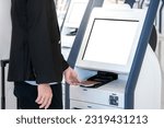 Well-dressed Businessman passenger using self service machine and help desk kiosk at airport terminal for check in, print boarding pass or buying ticket. Business travel and holiday trip concepts