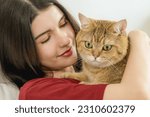 Small photo of A tender moment captured as a beautiful young woman, lying on her bed in the morning light, holds her cute cat closely. Their bond and affection are palpable
