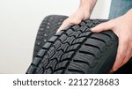 Small photo of Mechanic holding a tire at the repair garage. Replacement of winter and summer tires. winter studded tyre, tires replacement