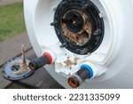 Small photo of Taking out an electric heater from boiler or water heater to remove lime scale residue on it as part of a maintenance.