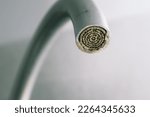 Selective focus on hard water deposit. Dirty faucet aerator with limescale, calcified shower water tap with lime scale in the kitchen, close up. A heavily calcified faucet