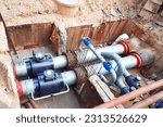 Small photo of Installing PVC pipe conduit running through trench filled with dirt. Laying heating pipes in trench at construction site. Pipes in the ground. Pipe replacement