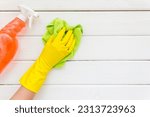 Female cleaner hand in yellow glove cleaning surface with duster.