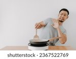 Small photo of Funny face newbie cooking asian man afraid fried oil isolated on background.