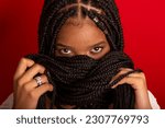 Close-up portrait of black woman with holding her braids to her face. Isolated on red background