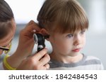 Otorhinolaryngologist examines little girl's ear with otoscope. Adenoiditis as cause of otitis media in children concept.