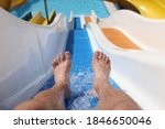 Male feet with splashing water on slide in water park. Entertainment in hotel pools and aquapark concept