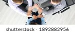 Small photo of Top view of businesspeople putting hands together in office. Good deal. Support and team work. Employees sitting on chairs in stylish suits. Business and career success concept