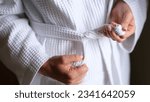 Small photo of Natural fabric and closeup of female hands tying belt of white robe