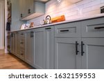 Kitchen cabinets with white countertop black handles and tile backsplash
