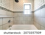 Small photo of Alcove bathtub shower combo with ceramic and subway tiles wall with mosaic tiles trim in the middle