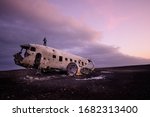 the man stand on the  abandoned DC Plane on Sólheimasandur in Iceland as one of the tourist destination