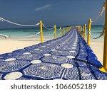 Small photo of Blue plastic bridge with yellow rail is the way through the sea.