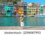 woman traveler visiting in Taiwan, Tourist with backpack and hat sightseeing in Keelung, Colorful Zhengbin Fishing Port, landmark and popular attractions near Taipei city . Asia Travel concept