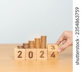 Small photo of flipping 2023 to 2024 year block with Coins stack. Money, Budget, tax, investment, financial, savings and New Year Resolution concepts