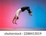 Small photo of guy acrobat doing back fat in new lighting, male dancer jumps and falls in the air on red blue background, hiphop performer does trick and levitates in the air