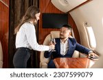 Small photo of female stewardess serving glass of champagne to asian businessman in private luxury jet, korean financier manager in suit flying in plane and ordering champagne, luxury lifestyle