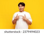modest young asian guy in white t-shirt feeling shy on yellow isolated background, confused korean man feeling embarrassed and feeling uncomfortable