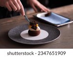Skilled chef meticulously garnishing dessert with rich chocolate, creating an exquisite culinary masterpiece in elegant fine dining setting