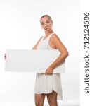 Small photo of Young jocular woman portrait of a confident businesswoman showing presentation, pointing placard gray background. Ideal for banners, registration forms, presentation, landings, presenting concept.