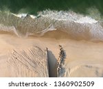 Small photo of Waves coming in on a pristine Leblon beach with the mouth of a canal contrived of partly constructed and partly placed rocks leading to the city lake.