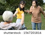 Small photo of Asian teen granddaughter dissuade her family from a big fight,angry senior mother ,aggressive daughter arguing violently,abusing,quarreling at park while traveling together,ungrateful,family problems