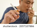Small photo of Male smoker holding a cigarette suffering from chronic cough,asian man patient coughing with sputum,respiratory problems,emphysema disease or lung cancer from smoking,medical and health care concept