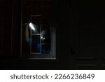 Small photo of Burglar breaking in to home in night through window. Burglar at night with flashlight at window of the house. Thief Breaking House Window To Enter House