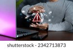 Small photo of Young business man hand using smartphone, laptop with warning sign for error notification and maintenance concept. Malicious software,virus and cybercrime, Cybersecurity,data.